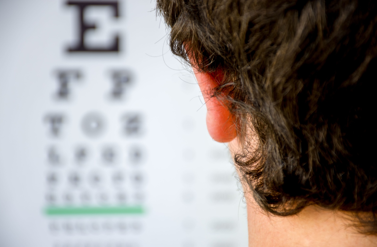 An over-the-shoulder view of a patient looking at a blurry eye chart.