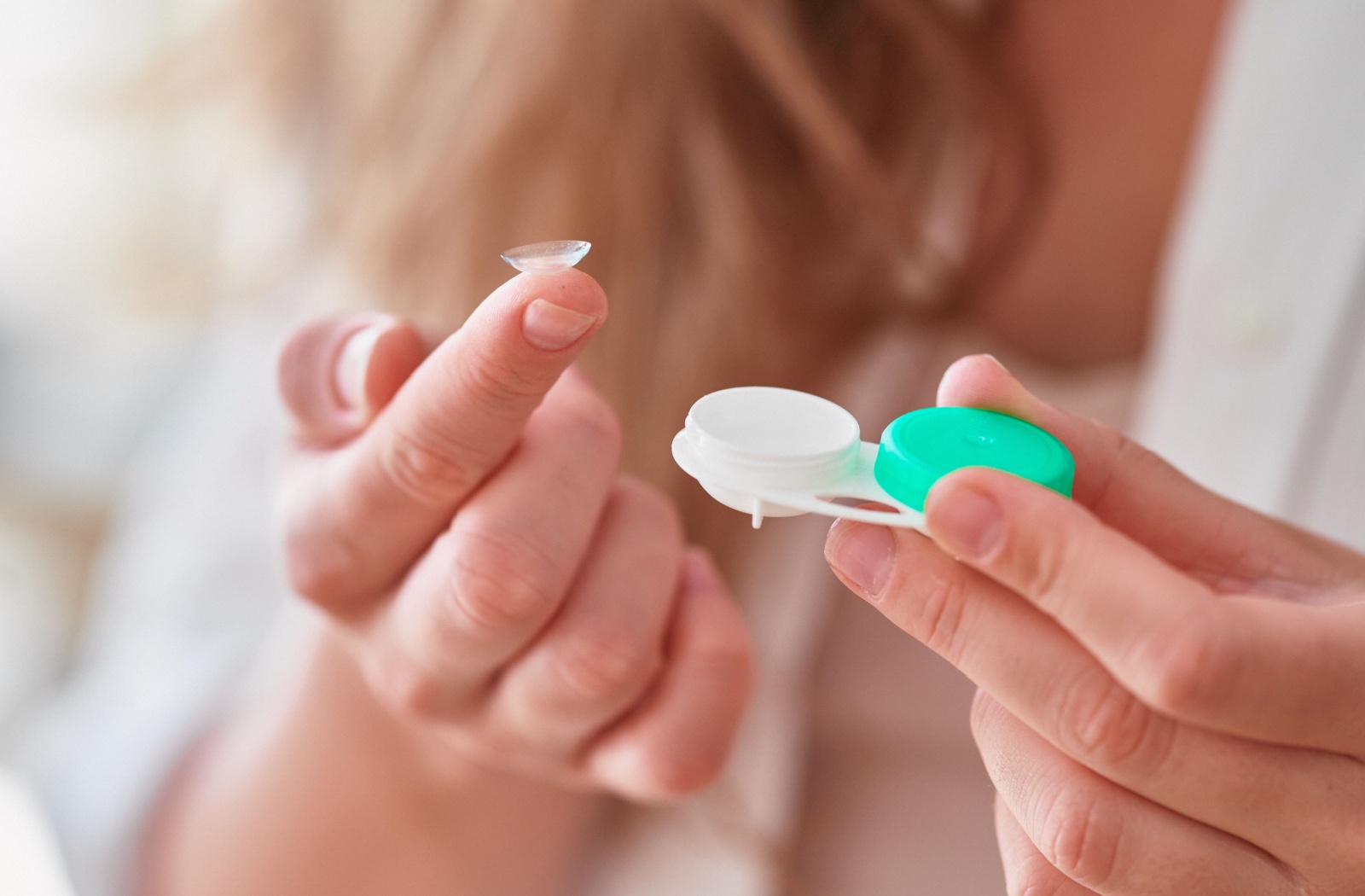 Person holding a contact lens with an open case.